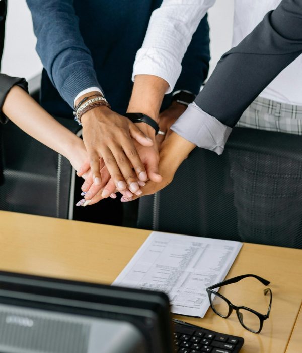 A close-up of a diverse business team stacking hands in unity, showcasing teamwork in an office setting.